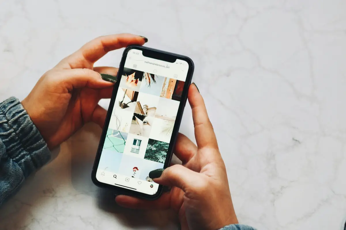 Two hands holding a smartphone that shows a web page