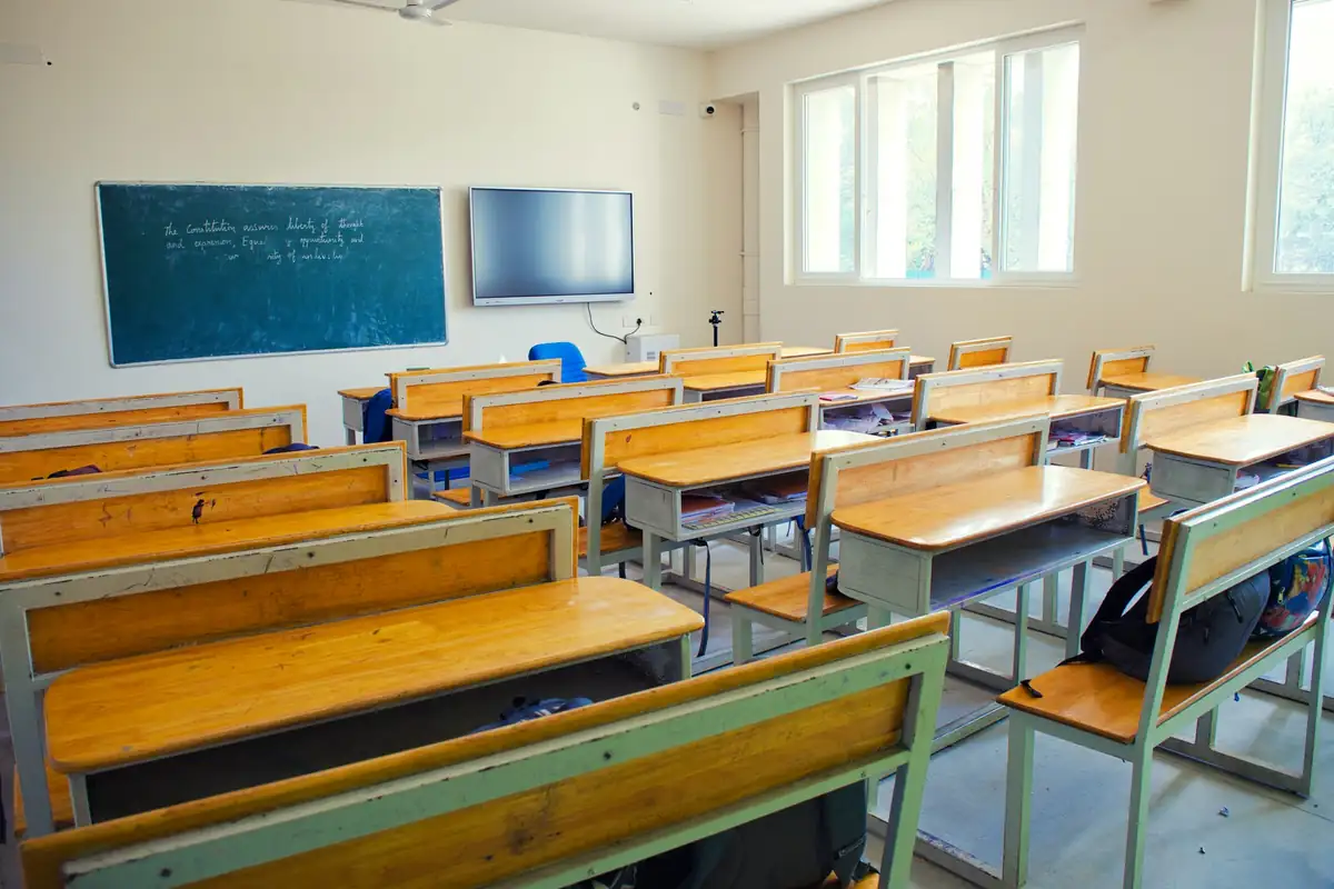 Empty classroom with wooden bench desks and a blackboard